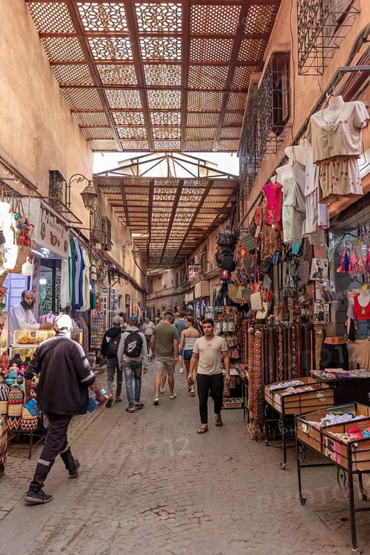 Covered market street with lots of people and colorful clothing stores