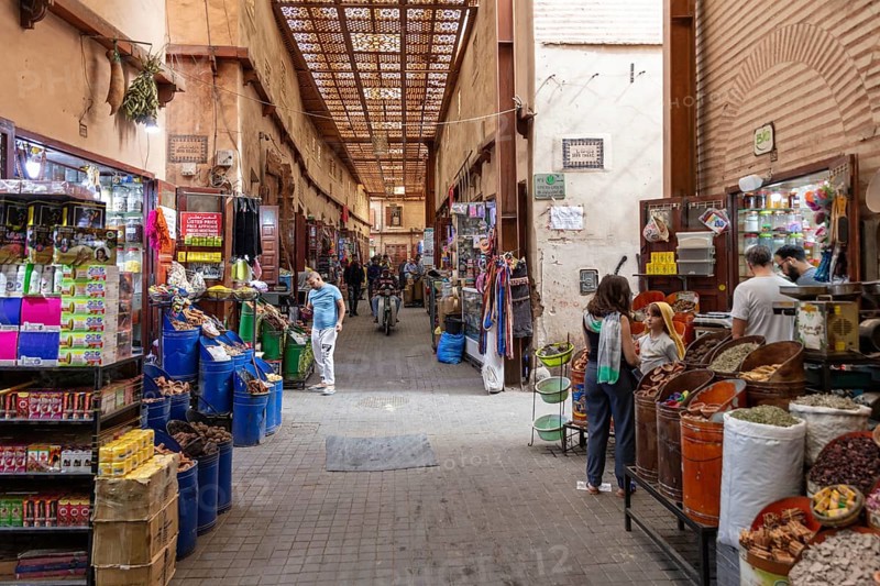 Lively, covered market street with various stalls and people shopping