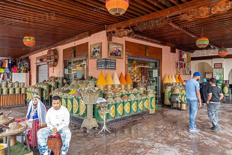 Market square with large, decorative vessels full of spices and people, inspired by Arabic