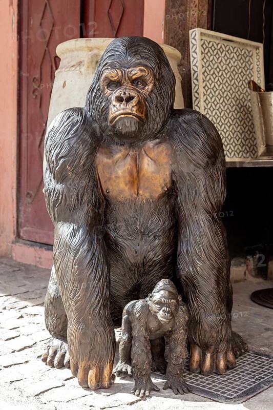 A large statue of a gorilla monkey with a young in a busy environment