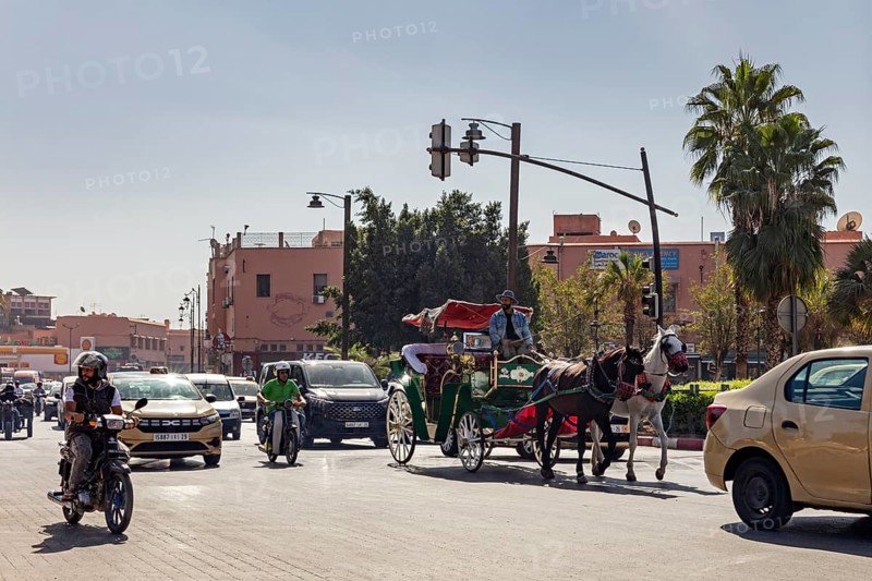 Street scene in a busy city with carriage, cars and motorcyclists
