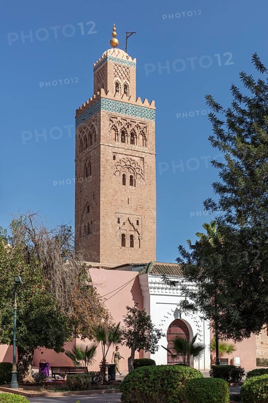 High tower of the Koutoubia Mosque against a blue sky surrounded by trees