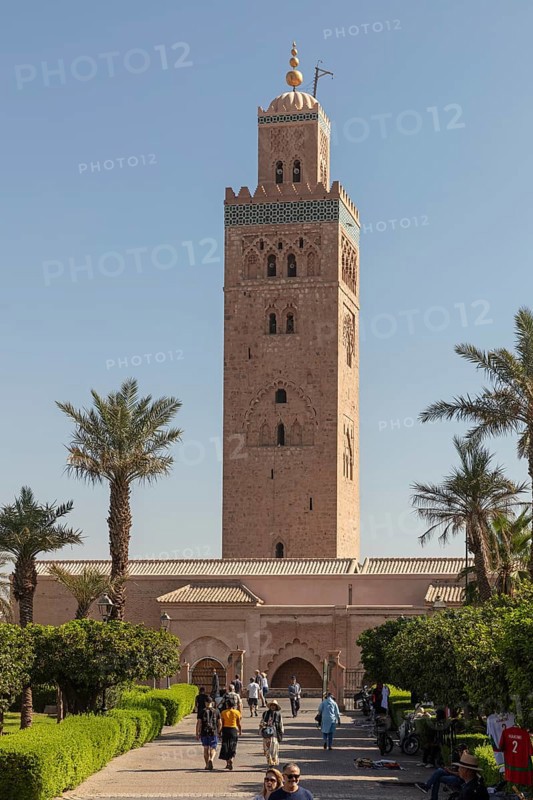 The towering minaret of the Koutoubia Mosque in Marrakech, surrounded by palm trees and visitors in good weather