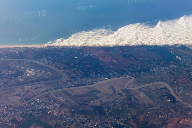 Aerial view of a coastal landscape with waves, agricultural fields and an airport