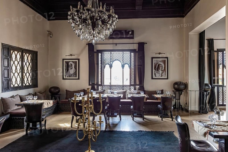 Elegant restaurant dining room with chandeliers, black and white paintings and large windows