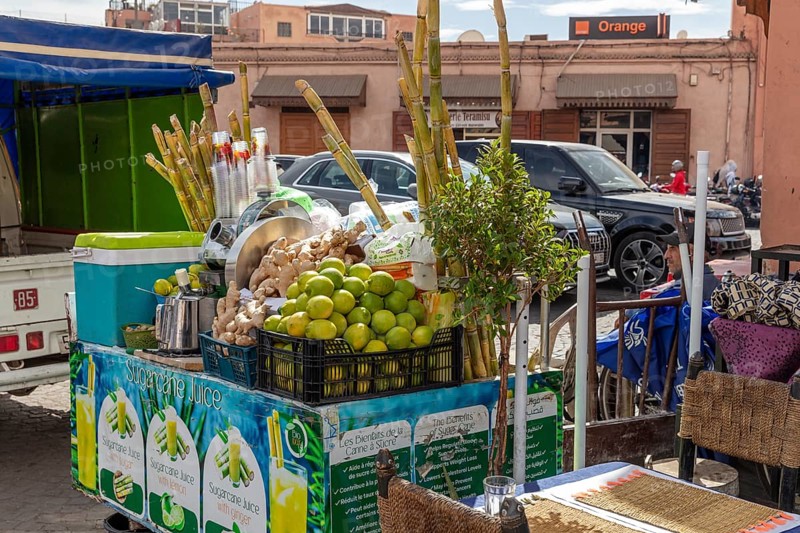 Lively street stand with fresh fruit and sugar cane for juices at a busy market
