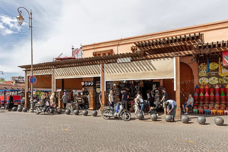 Lively market street with kiosks, traffic and people in sunny weather