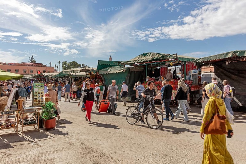 Lively market with people, bikes and stalls under a blue sky