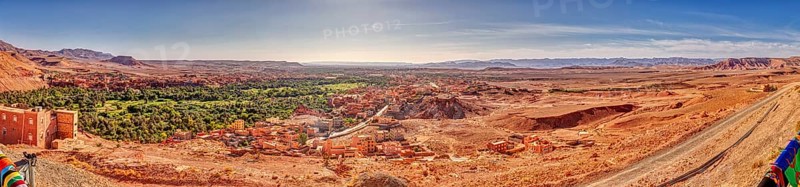 Wide desert landscape with oasis and village under a clear sky