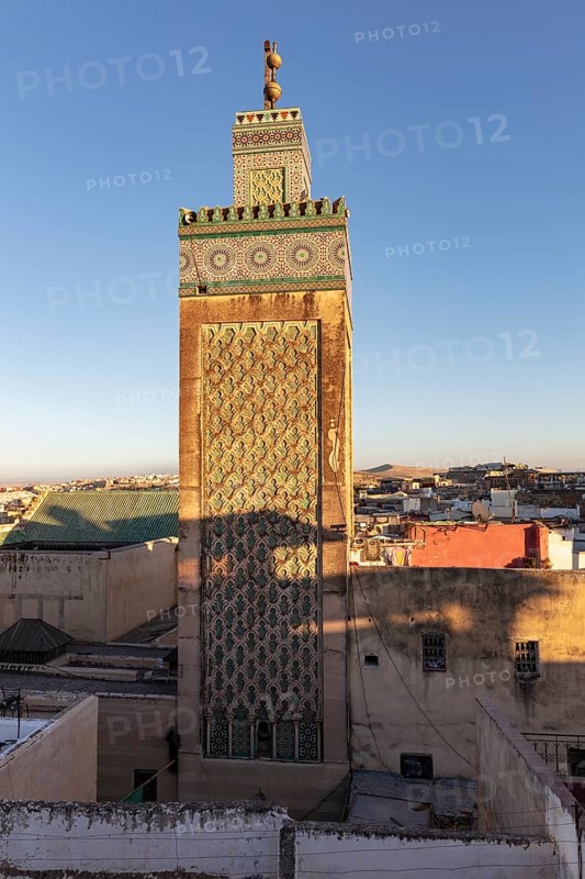 Decorated minaret over the cityscape in the light of the setting sun