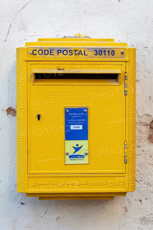 Yellow letterbox on a wall with Arabic and French letters