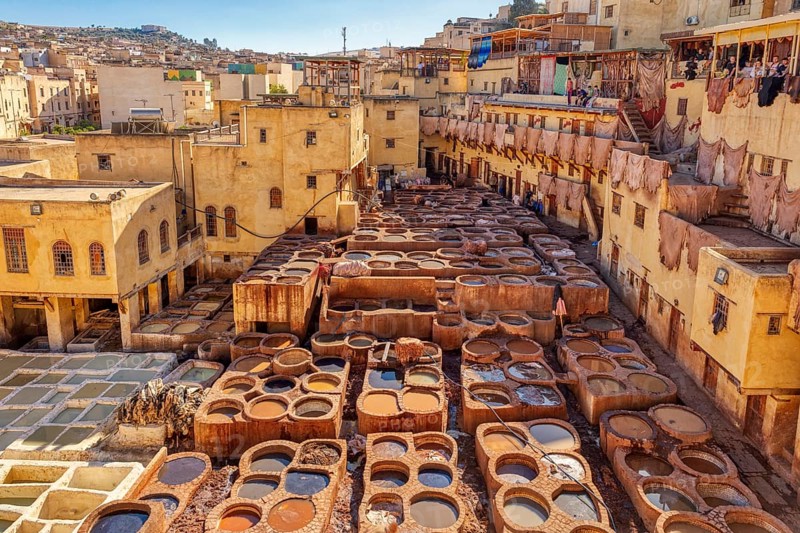 The bustling atmosphere of a traditional old town tannery, illuminated by warm sunlight and marked by craftsmanship