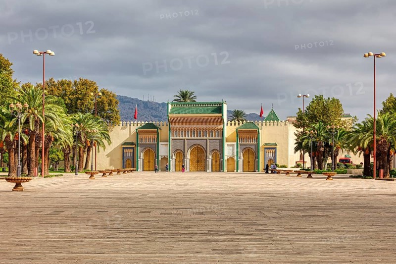 Large palace complex with arches and palm trees in a spacious courtyard