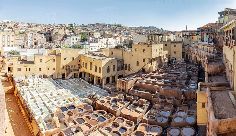Traditional tannery in Fez under clear skies with numerous leather troughs