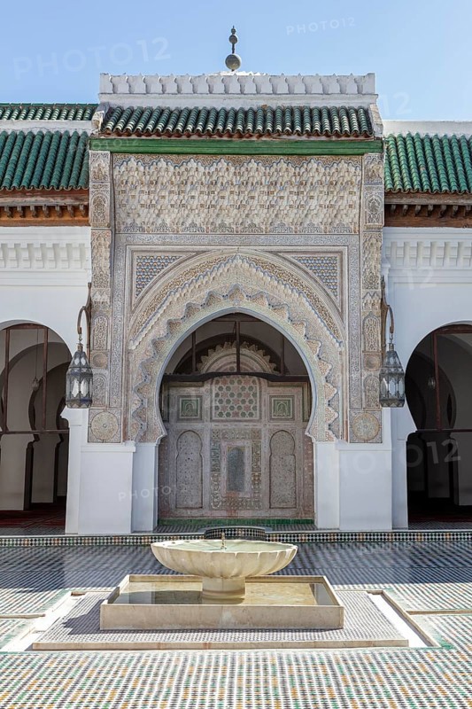 A richly decorated Islamic building with a central well, surrounded by mosaics and Islamic architectural elements