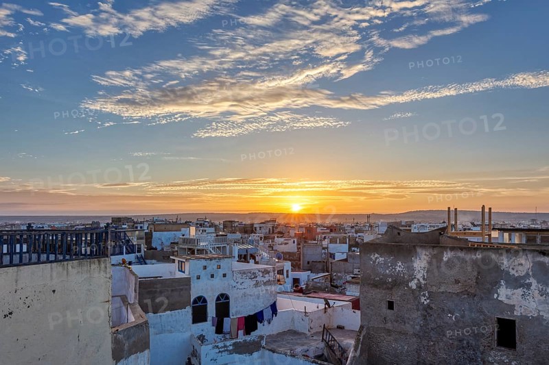 City panorama at sunrise with warm sky tones and scattered clouds over flat buildings