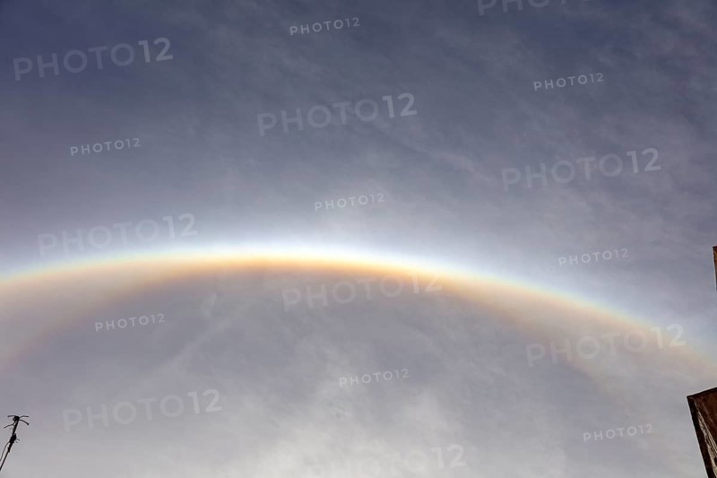 Glowing semicircular halo on cloudy sky