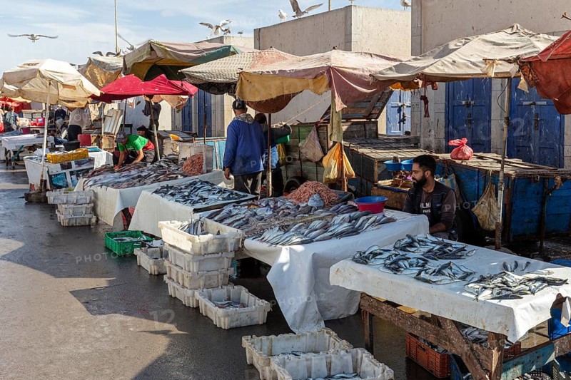 Market scene with fish stalls and vendors, colorful umbrellas and people in a peaceful atmosphere