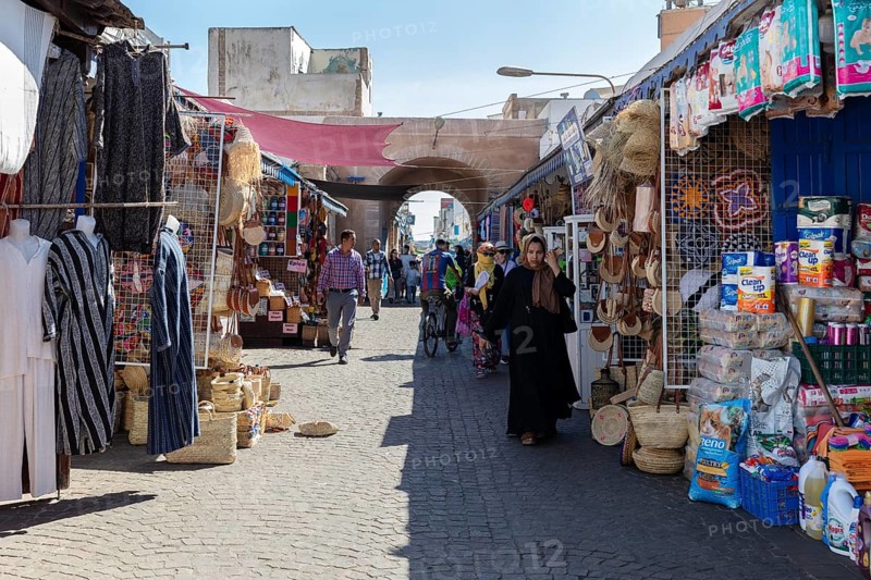 Bustling market street with numerous stalls and archways under the sun
