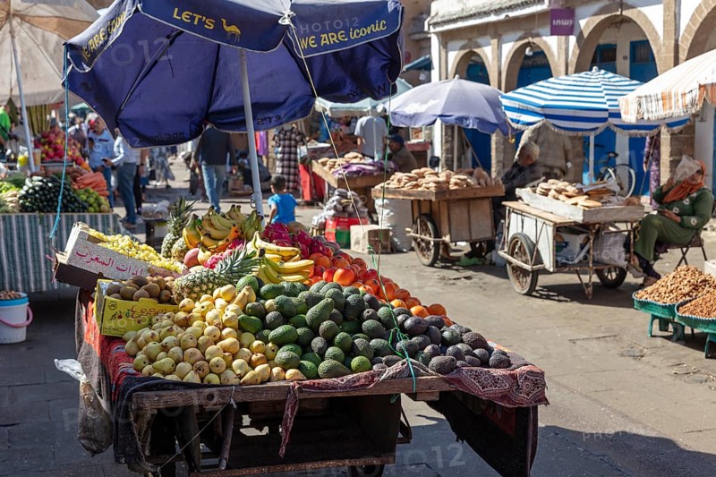 Fertile market stand under umbrellas with a variety of fruits and customers