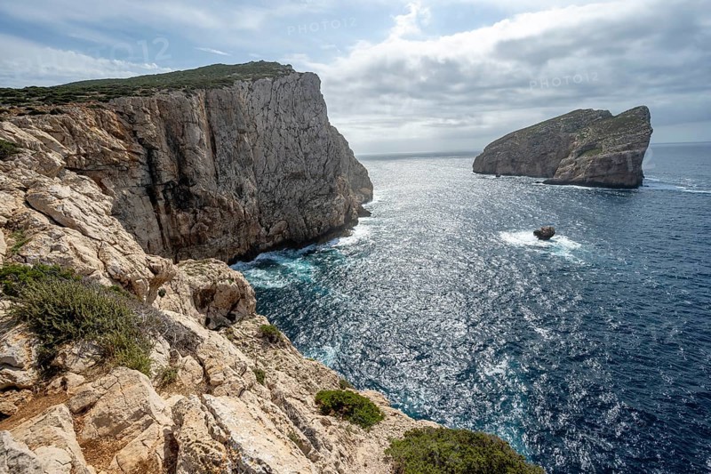 Steep cliffs by the sea and the rocky island of Isola Foradada, Belvedere Foradada, cliffs on the Capo Caccia headland, Alghero, Sardinia, Italy