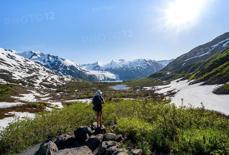 Hiker enjoys views from Portage Pass of Divide Lake, snowy mountain peaks and glaciers Portage Glacier, Portage Pass Trail, near Whittier, Alaska, USA