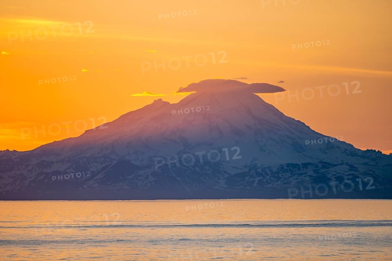 View of Cook Inlet on white mountain peaks of Mount Redoubt at sunset, picturesque golden light of the midnight sun, mountains of the Aleutian Range, Anchor Point, Anchor River State Recreation Area, Alaska, USA