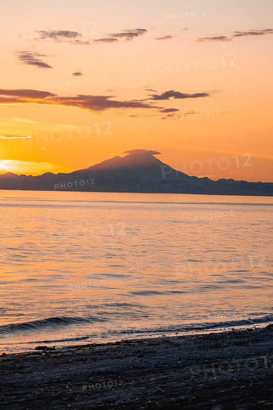 View of Cook Inlet on white mountain peaks of Mount Redoubt at sunset, picturesque golden light of the midnight sun, mountains of the Aleutian Range, Anchor Point, Anchor River State Recreation Area, Alaska, USA