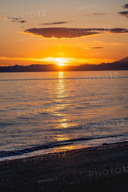 View of Cook Inlet at sunset, picturesque golden light of the midnight sun, mountains of the Aleutian Range, Anchor Point, Anchor River State Recreation Area, Alaska, USA