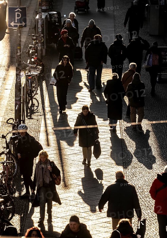 Passers-by on a Friedrichstraße sidewalk in Berlin, shade, low sun, winter, Germany