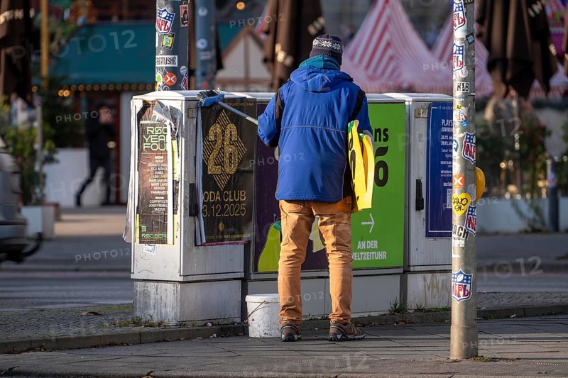 Man sticks posters to electrical boxes near Alexanderplatz, Berlin, Germany
