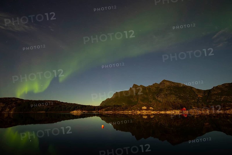 Northern lights are reflected in the fjord in Norway. Aurora Borealis over Festvåg near Bodø, Nordland, Norway