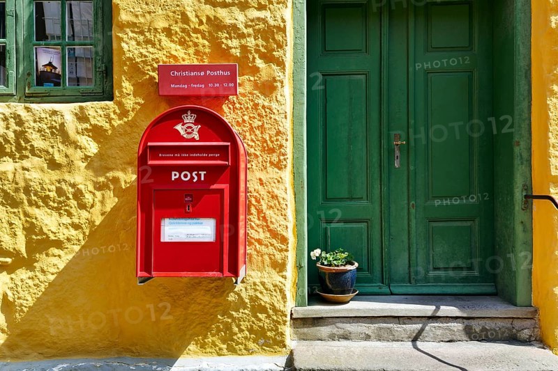 Post office, façade detail, red mailbox with post horn and crown, green wooden door, yellow wall, Christiansø, Christiansö, Ertholmene, Pea Islands, Bornholm, Baltic Sea, Denmark