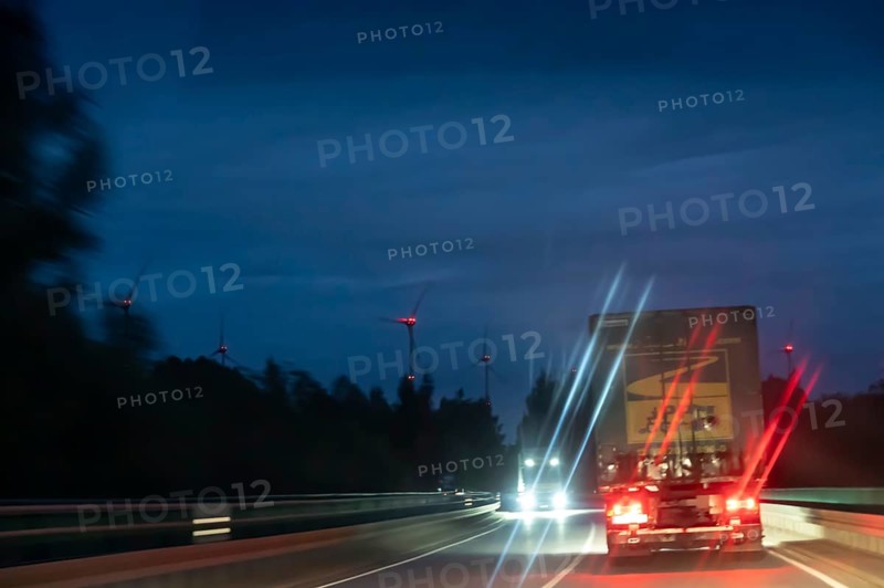 Truck on federal highway at night, wind turbine lights on the left, Schleswig-Holstein, Germany