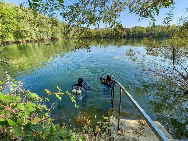 Recreational divers with diving equipment Diving tanks swim near the shore on the water surface of a small lake, Germany