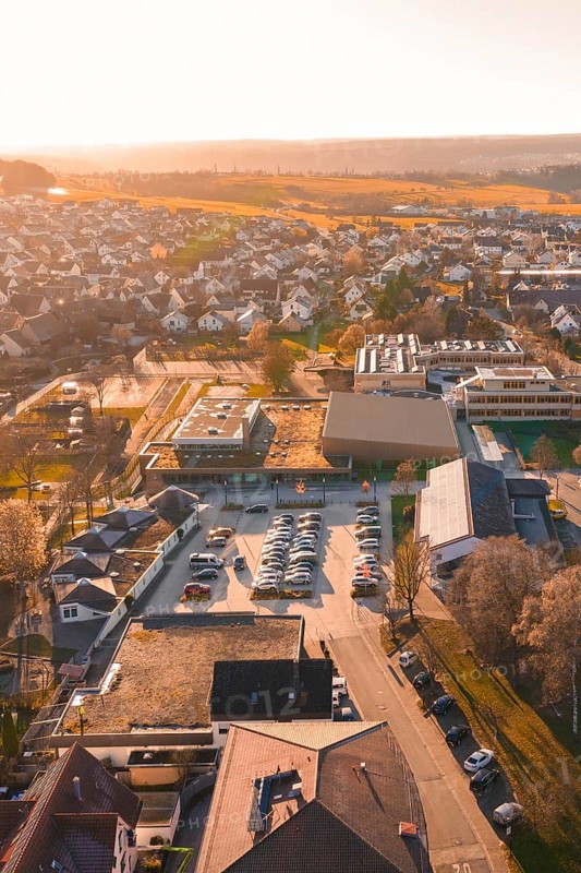 Aerial view of a village at sunset with parked cars and houses, sports center and swimming pool Althengstett, Calw district, Germany