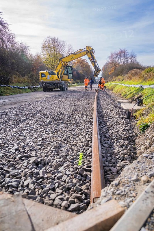 Crane aligning ballast on a construction site, workers watching, Hermann Hesse Railway track construction, Calw, Germany