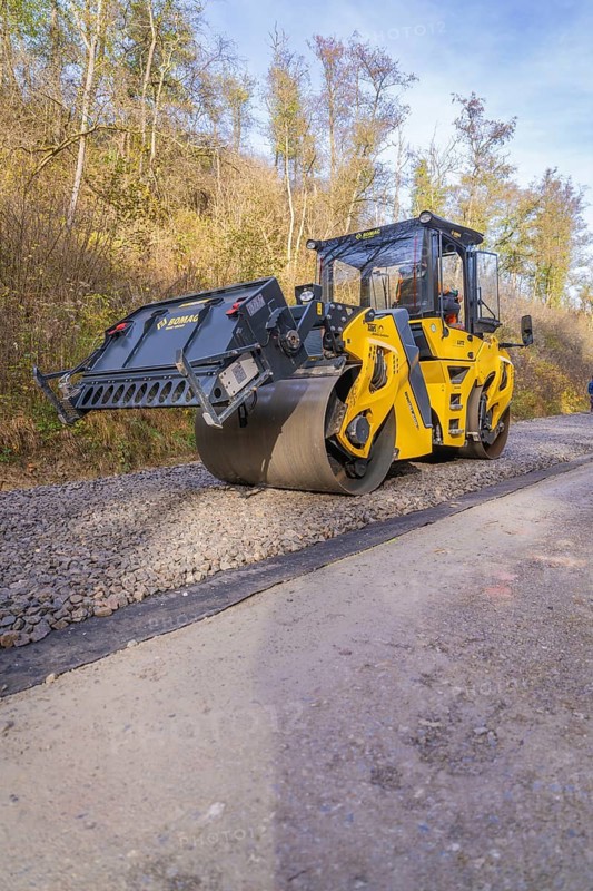 Yellow road roller on a construction site surrounded by autumn trees, Hermann Hesse Railway track construction, Calw, Germany
