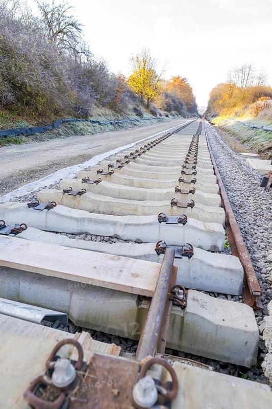 Behind a railroad, a long, straight section of track stretches through autumnal nature, track construction of the Hermann Hesse Railway, Calw, Germany