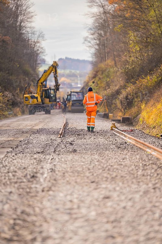 Road construction with construction workers and cranes on a gravel road in autumn, track construction of the Hermann Hesse Railway, Calw, Germany