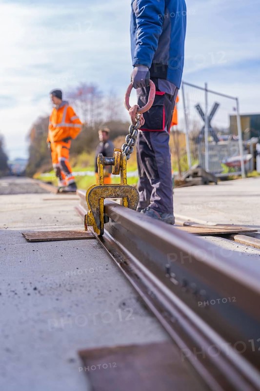 Close-up of a rail with hook, workers in the background with orange vests, Hermann Hesse Railway track construction, Calw, Germany