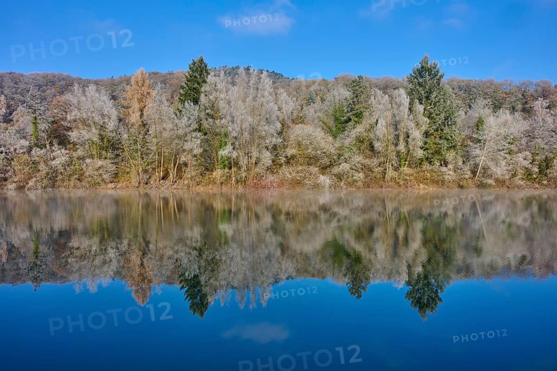 A quiet autumn picture with a lake whose water reflects an autumnal forest, hoarfrost, winter, Mondsee, Mondfeld, Wertheim, Main-Tauber-Kreis, Baden-Württemberg, Germany