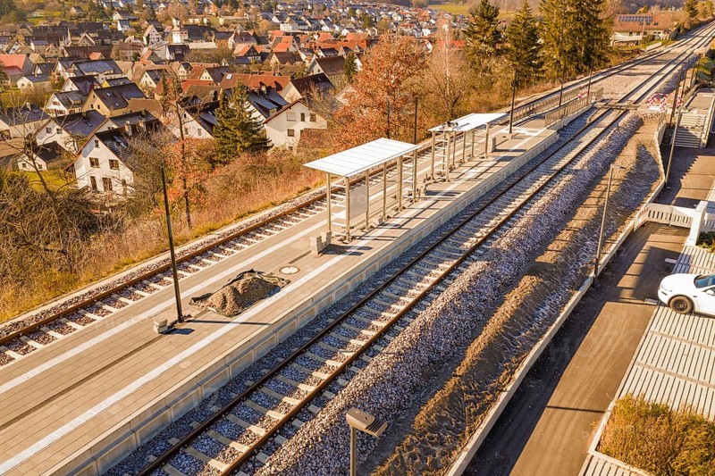 Aerial view of a rural train station with platform roof and tracks in the village, new Hermann Hessebahn station, Ostelsheim, Calw district, Germany