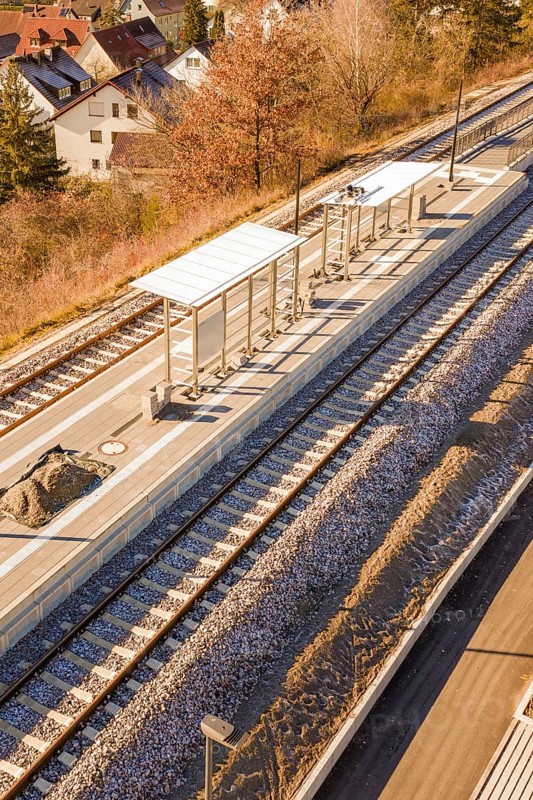 Station with platforms and tracks, surrounded by autumn leaves and houses, seen from a bird's eye view, new Hermann Hessebahn station, Ostelsheim, Calw district, Germany