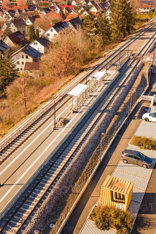 Aerial view of a small train station with parked cars surrounded by autumn vegetation and a village, new Hermann Hessebahn railway station, Ostelsheim, Calw district, Germany