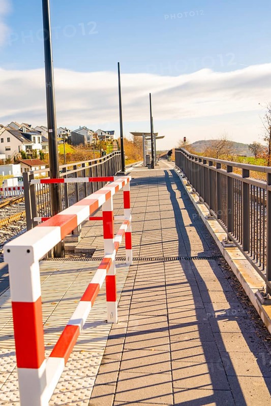 Footbridge with modern barrier and cast shadows in sunshine, new Hermann Hessebahn railway station, Ostelsheim, Calw district, Germany
