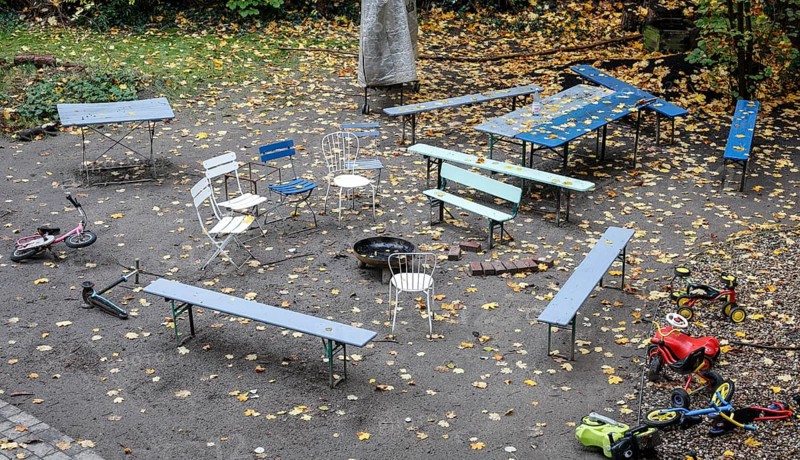 Chairs and tables stand unsorted around a fire bowl, a celebration in the garden is over, colorful autumn leaves everywhere, Berlin, Germany