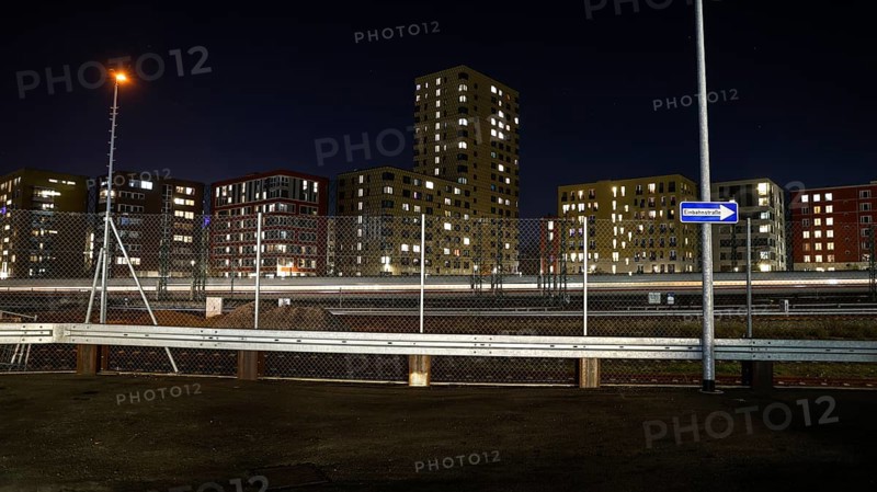 One way street on the fence, behind it a passing ICE train, illuminated apartments in a new housing development, Berlin, 23.11.2025, Berlin, Berlin, Germany