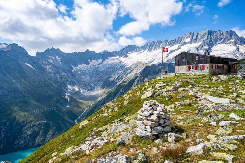 Mountain hut Bergseehütte with Swiss flag in picturesque mountain landscape, view of Damma Glacier and Dammastock, Göscheneralp, Canton of Uri, Switzerland