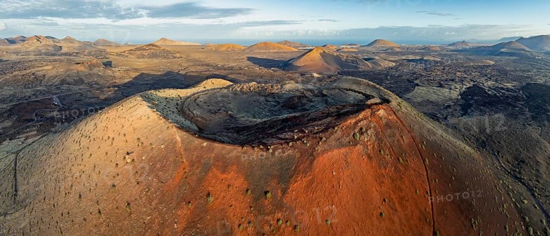 Caldera Colorada volcano, picturesque volcanic landscape with volcanic craters and lava fields in morning light, Parque Natural de Los Volcanes, aerial view, Lanzarote, Canary Islands, Spain